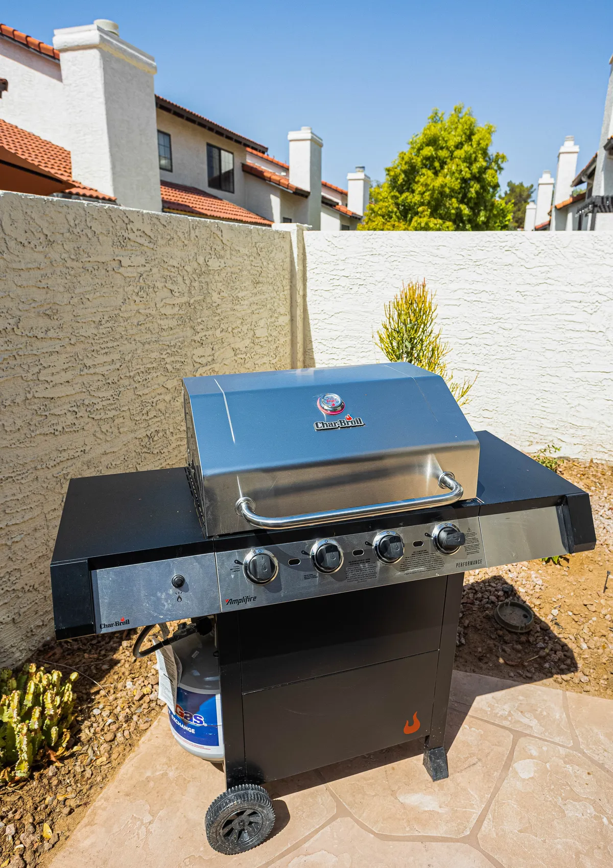 The backyard grill is set against a backdrop of lush landscaping and a secure fence, ready for barbecues and outdoor dining. The cheerful setup encourages social gatherings and celebrates the enjoyment of Arizona's outdoor lifestyle.
