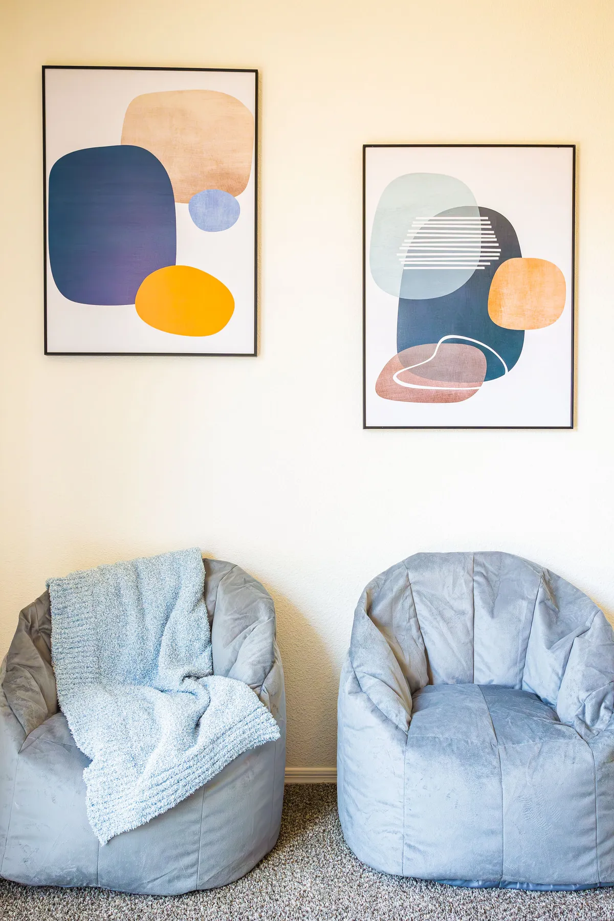 A modern, comfortable corner with two plush bean bag chairs and abstract wall art. The setting is ideal for relaxing, reading, or casual conversation, with a welcoming and cozy vibe.