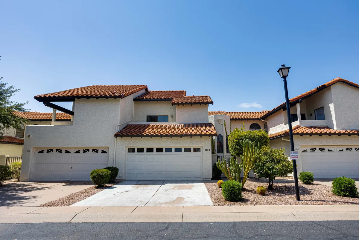 A wide exterior shot of the home, displaying its inviting stucco exterior, tiled roof, landscaped front garden, and spacious driveway. The presence of a street lamp and manicured garden beds sets a welcoming tone for family arrivals and gatherings.