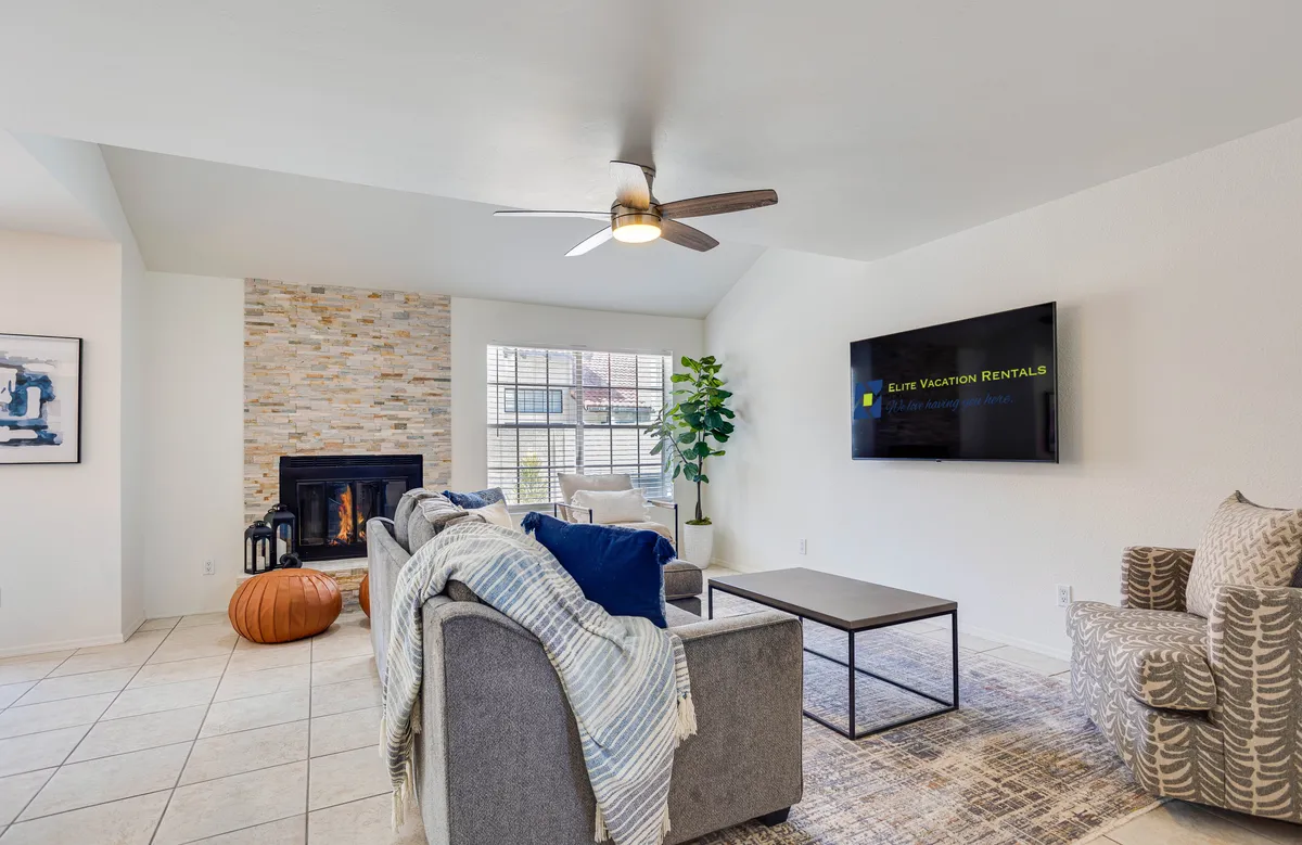 A cozy and elegant clubhouse interior featuring a fireplace, comfortable sofa, TV, coffee table, and houseplant. The space is inviting and well-appointed, perfect for socializing, relaxing, or hosting gatherings.